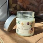 Bougie artisanale Fruit de la passion Les Lueurs d’Horion ouverte, montrant la cire blanche dans un pot en verre sur une surface en bois.